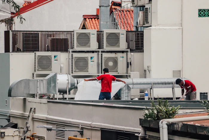 Crew working on a commercial rooftop with condensing units and ductwork