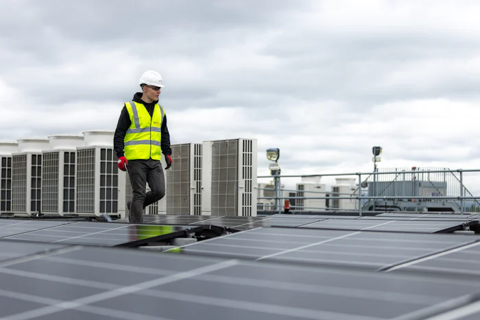 Technician walking a commercial roof lined with rooftop HVAC units